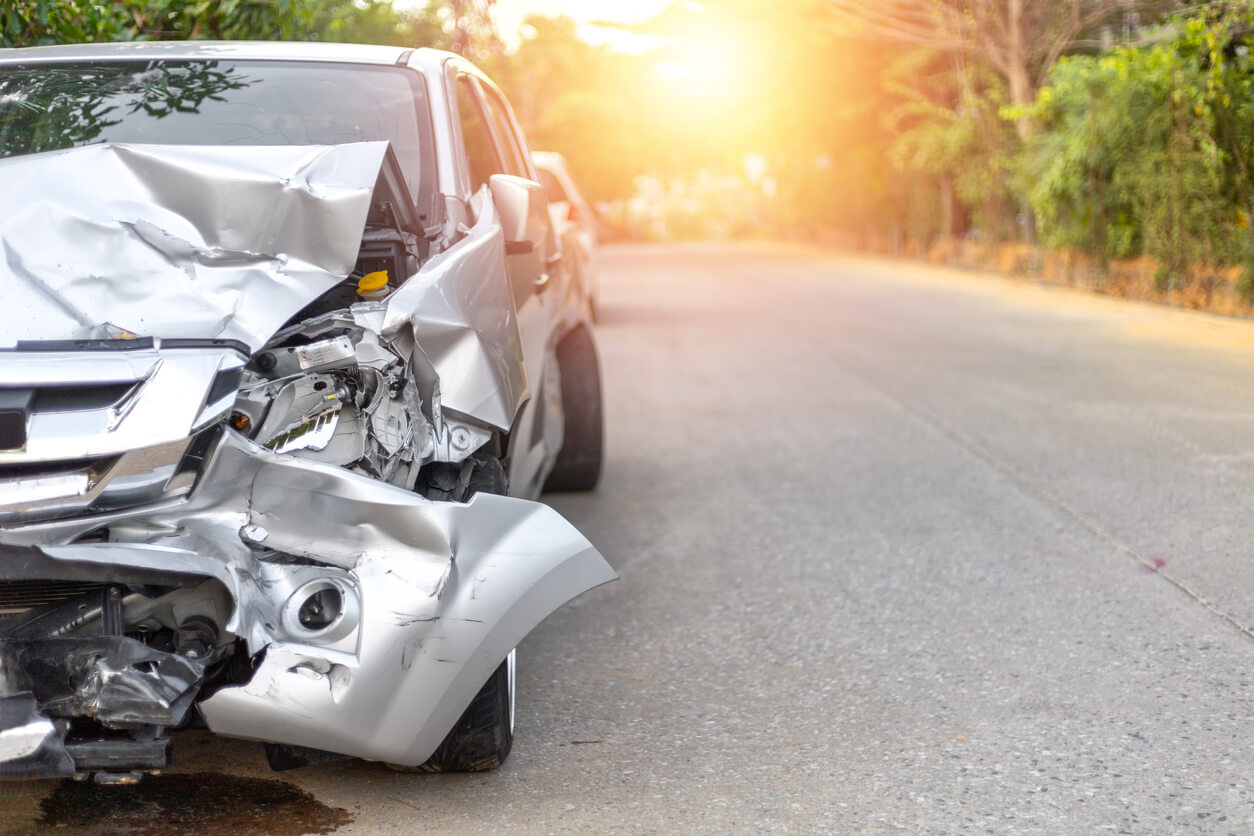 Car accident with silver vehicle on the side of the road.