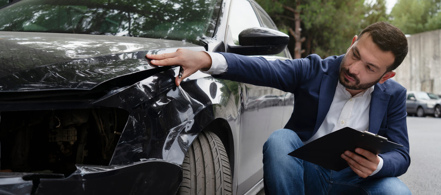 insurance adjuster looking at car from accident