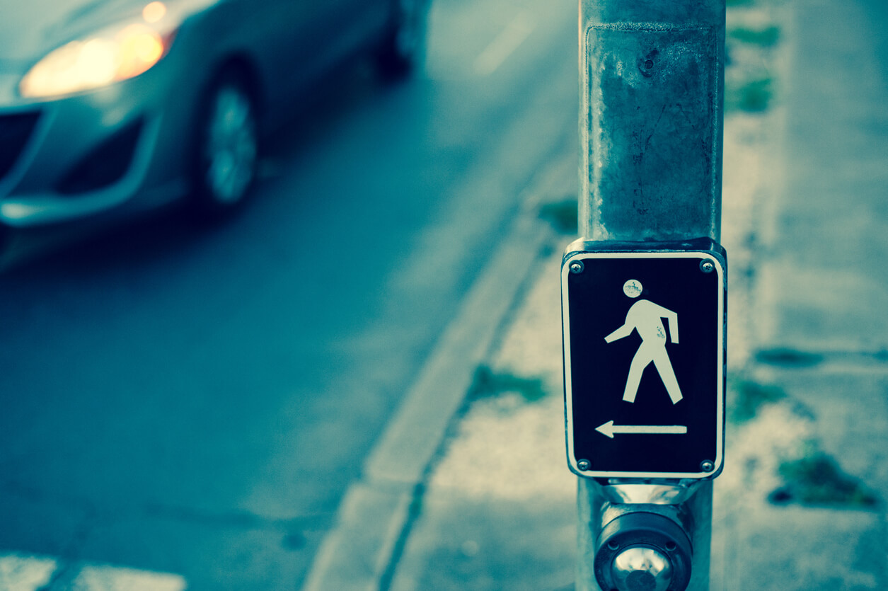 Pedestrian Accidents person walking sign on metal pole pointing to crosswalk