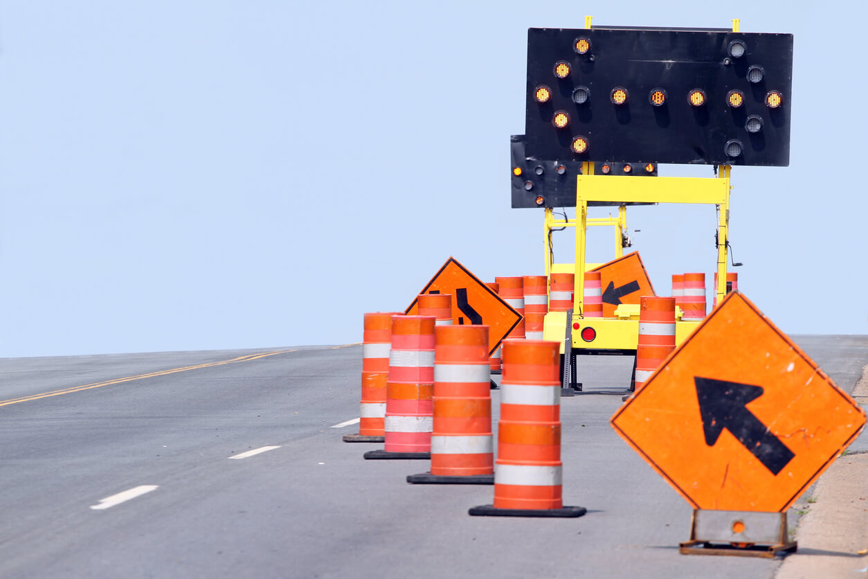 Road Construction Accidents cones with large arrow digital sign and small orange arrow sign on road