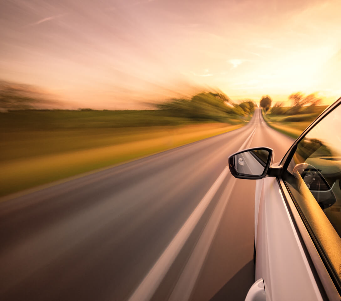 Speeding Car Accidents side view of drivers side of car driving fast down the road